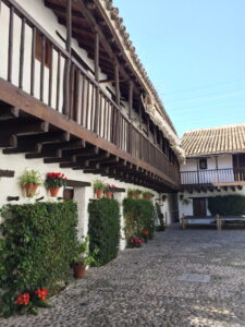 Historischer Innenhof in Córdoba mit weißen Häusern, Holzbalkonen und Blumen