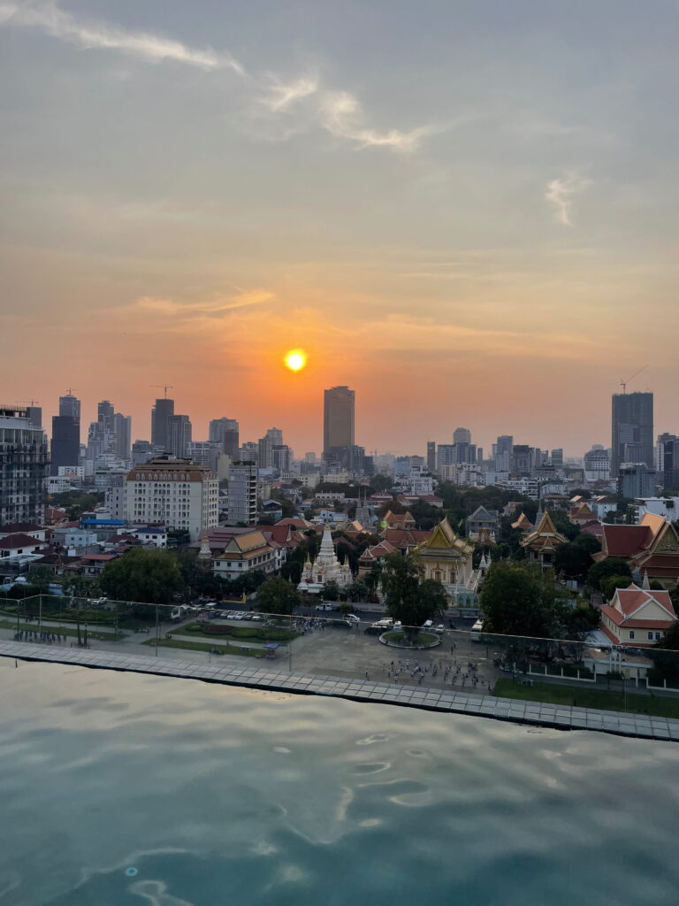 Sonnenuntergang über Phnom Penh mit Blick vom Rooftop-Pool auf den Königspalast und die Skyline der kambodschanischen Hauptstadt